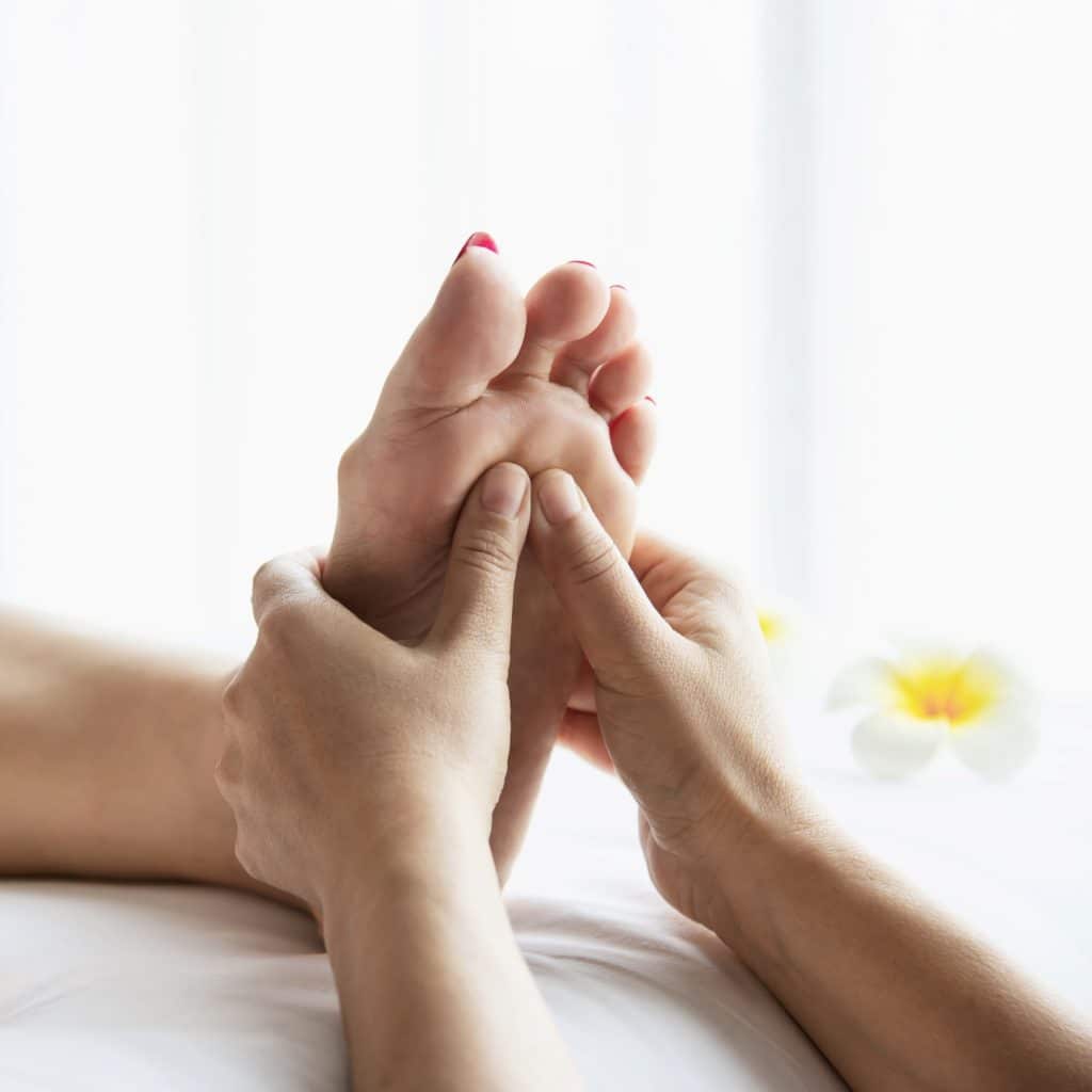 gros plan sur les mains et pieds d'une séance de reflexologie