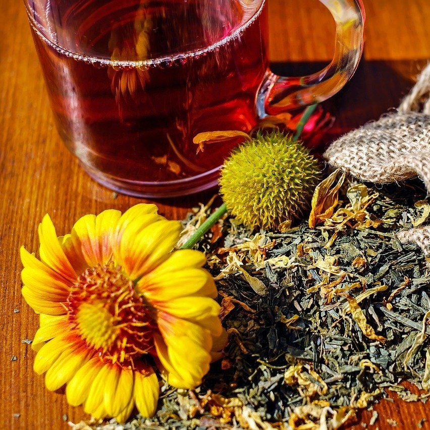 il y a une tasse de tisane, une fleur, des herbes sèches